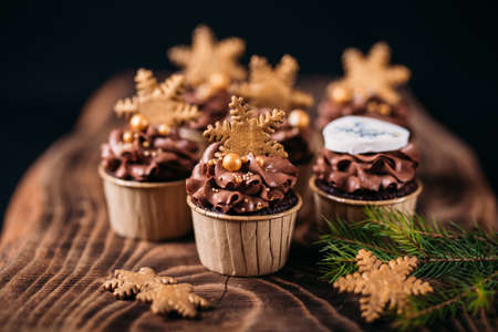 Chocolate cupcakes with star shaped cookies on a wooden background. Christmas mood. Sweets for any occasionの写真素材