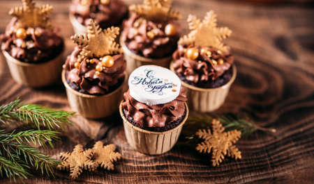 Chocolate cupcakes with star shaped cookies on a wooden background. Christmas mood. Sweets for any occasionの写真素材