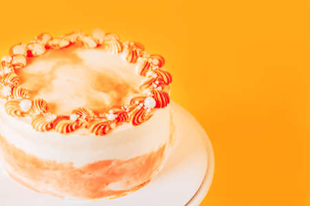 Beautiful carrot cake on a stand. Sweets for any occasion. Birthday and Christmas present. Opposite yellow backgroundの写真素材