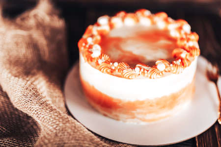 Cake on a white plate with a fork in front of a wooden background. Sweets for any holiday