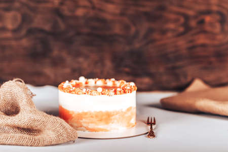 Cake on a white plate with a fork in front of a wooden background. Sweets for any holidayの写真素材