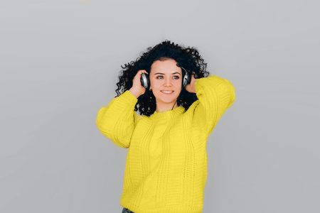 Photo of young beautiful woman on gray background wearing bright yellow illuminating sweater. Color year 2021.の写真素材