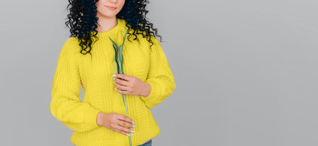 Photo of young beautiful woman on gray background wearing bright yellow illuminating sweater. Color year 2021.の写真素材