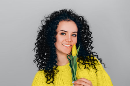 Photo of young beautiful woman on gray background wearing bright yellow illuminating sweater. Color year 2021.の写真素材
