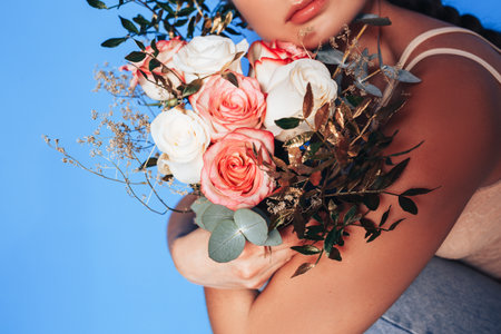 Young woman holding a beautiful bouquet of white roses in her hands, woman hugging a bouquet of roses in a holiday.の写真素材