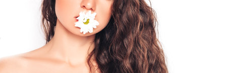Young woman on white background with lower in her mouth. face care. oil, lip balm.の写真素材