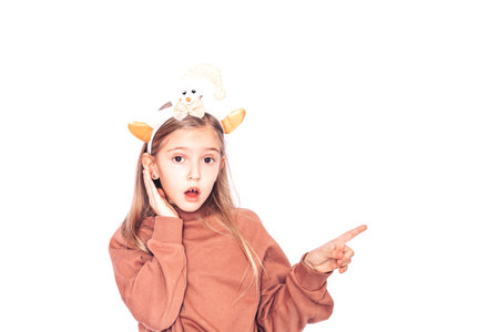 A surprised child points to the side. There is a rim with horns on the childs headの写真素材
