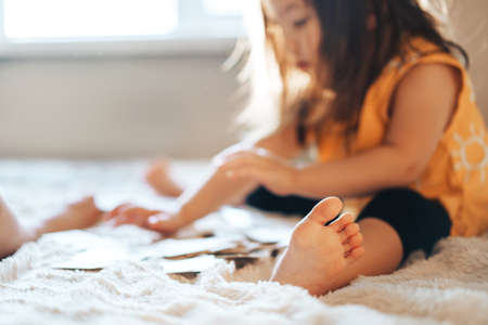 The child plays educational games in the room on the bed. The child learns numbers and letters by cards. Raising and caring for children.の写真素材