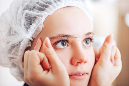 Cosmetolog beauty master making marks with a thread before the permanent makeup procedureの写真素材