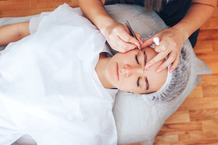 Cosmetolog beauty master making marks with pencil before the permanent makeup procedureの写真素材