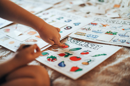 The child plays educational games in the room on the bed. The child learns numbers and letters by cards. Raising and caring for children.の写真素材