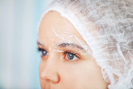 The master cosmetologist doing anesthesia and pain relief before the permanent makeup procedure.の写真素材