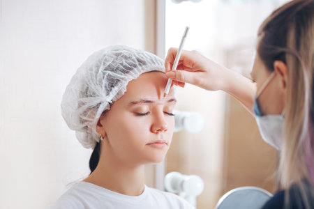Cosmetolog beauty master making marks with pencil before the permanent makeup procedure.の写真素材