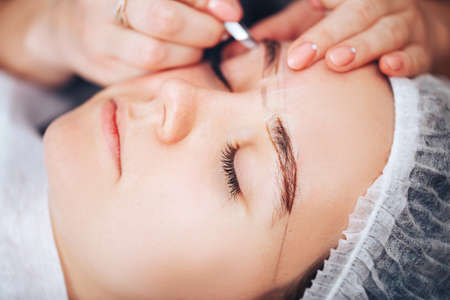 Cosmetolog beauty master making marks with pencil before the permanent makeup procedure.