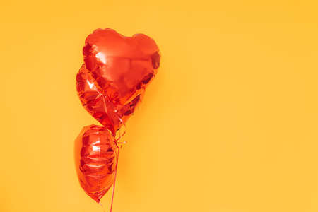 Red inflatable balloons against a yellow background. Gift for Valentine's Day, February 14, March 8 and Women's Day.の写真素材