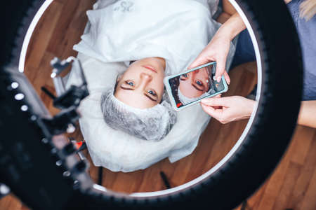 the beautician takes a photo of his work after the permanent makeup procedure.の写真素材