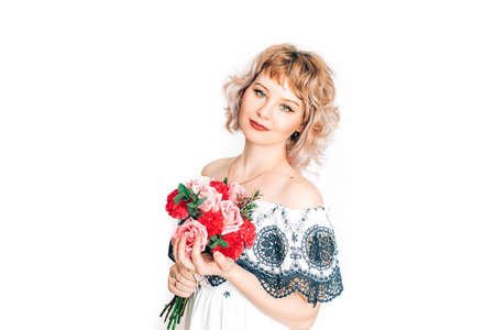A woman in a dress holding a beautiful bouquet of flowers in front of a white background. Holiday gift.の写真素材