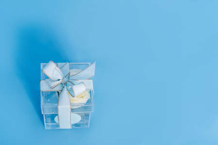 Glass transparent container wrapped in a bow with a white rose inside. Holiday giftの写真素材