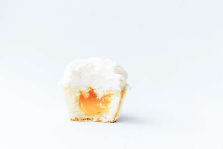 A beautiful appetizing white cupcake cut in half against a white background. Sweet dessert for any...