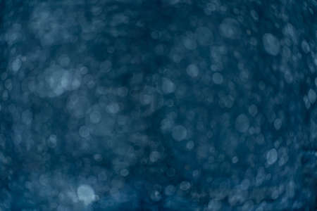 Beautiful blurry sparkles on blue background. Liquid soap in bottle close up.
