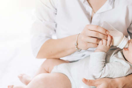 Caring mother bottle feeds her newborn baby. Caring for the health of children. Artificial feeding of children.の写真素材
