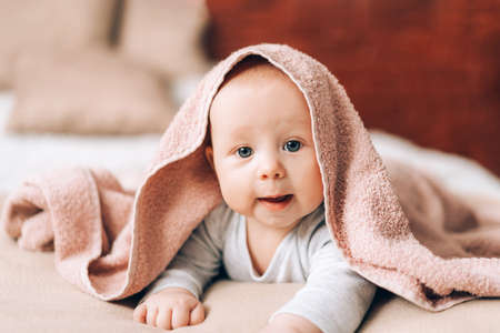 A beautiful newborn baby lying on his stomach and covered with towel. Caring for the health of...