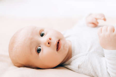 Small child lies on the bed and looks at the camera. Love and care for children. Adoption of...