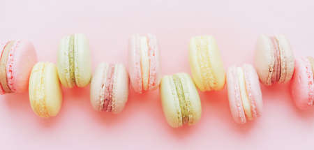Background of Macaroons of different colors lie in a row against a pink background. A gift for a loved one. Delicious dessert for any occasion.の写真素材