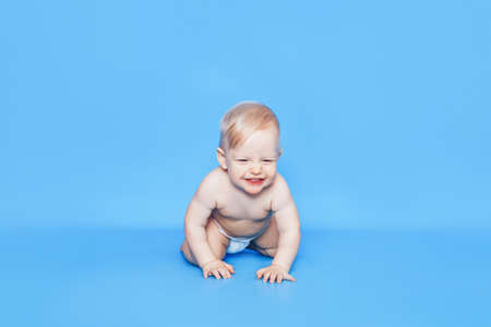 A small child is crawling on a blue background. Caring for the health of young childrenの写真素材