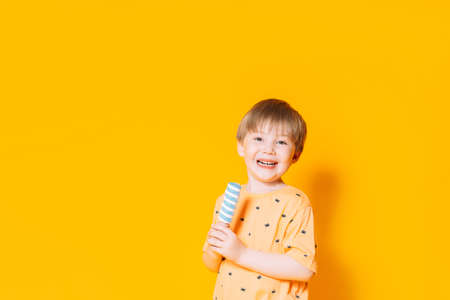 Little boy holding striped ice cream on a stick in his hands. Summertime.