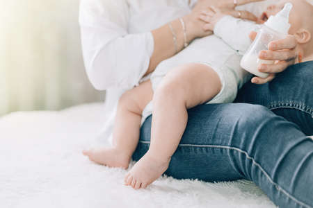 Caring mother bottle feeds her newborn baby. Caring for the health of children. Artificial feeding of children.の写真素材