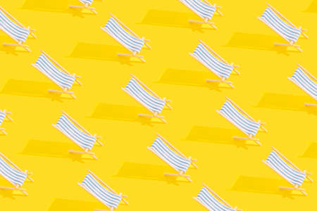 Summer pattern of sun loungers with bright sunlight on yellow background. Vacation concept.の写真素材