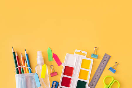 School supplies with medical mask and antiseptic on yellow background.の写真素材