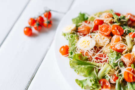 White plate with quail egg and cherry tomato salad on white boards.の写真素材