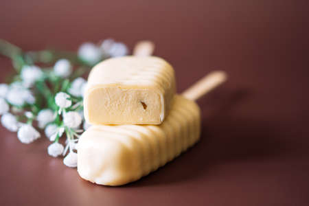 White Chocolate Popsicles cut with filling lying on top of each other on brown backgroundの写真素材