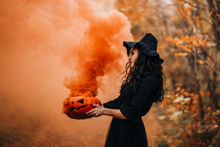 Orange smoke from pumpkin holding girl in witch costumeの写真素材