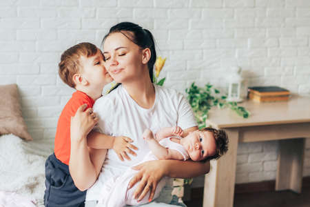 Little boy kisses his mom. Young mother holding nursing baby.の写真素材