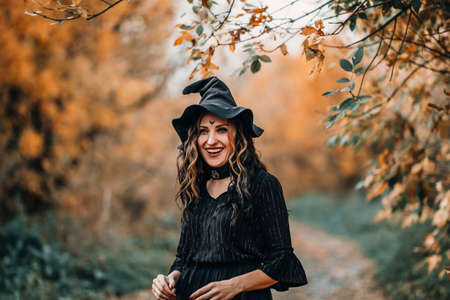 Girl dressed as witch laughs on the background of the forest.の写真素材