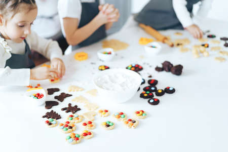 Children prepare cookies with sweets, a boy rolls out the dough with a rolling pin. Leisure activity...