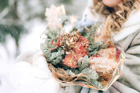 Woman holding a beautiful bouquet of flowers in her hands on a background of snow. Winter time. Gift for a holiday bouquet of flowers.の写真素材