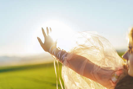 The girl covers the sun with her hand, the sun's rays make their way through her fingers.の写真素材