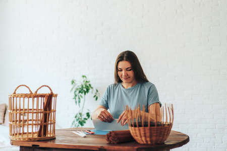 Woman sitting at table preparing basket weaving material.の写真素材