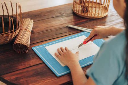 Girl cuts paper in half with stationery knife.
