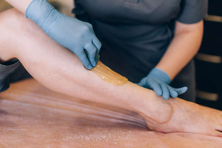 The specialist depilates the hair with shugaring on the leg.の写真素材