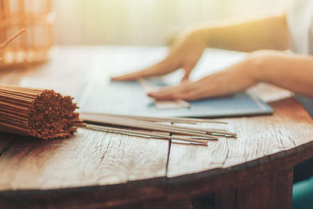 Woman twirls tubules for weaving on the background of bundle of tubules.の写真素材