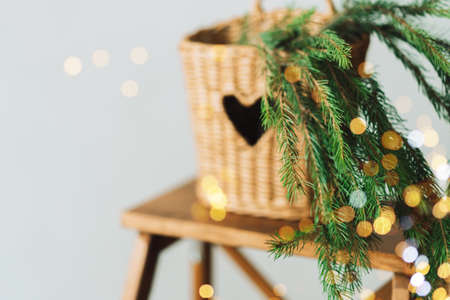 Branch of Christmas tree in wicker basket on wooden stepladder with garland.の写真素材