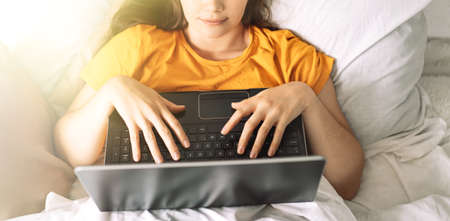 Girl makes online purchases through laptop while sitting in bed