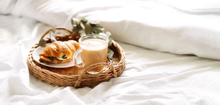Breakfast in bed with croissant and coffee on trayの写真素材