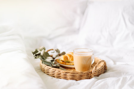 Breakfast in bed with croissant and coffee on tray.の写真素材
