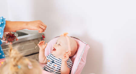 Mom feeds her baby at home red currants.の写真素材